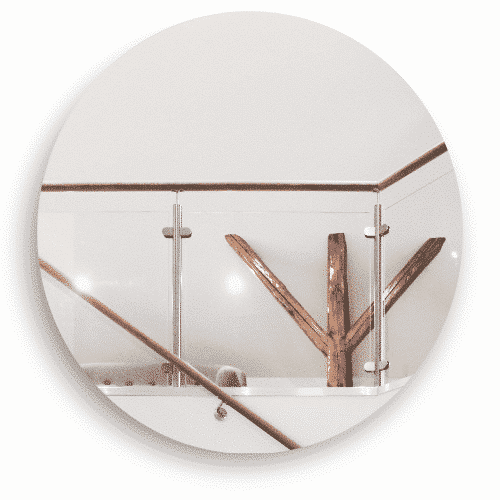 Ein Glasgeländer für den Innenbereich mit Edelstahlpfosten und einem Holzgeländer. Das Geländer umgibt einen offenen Bereich, in dem ein dekoratives Holzdetail zu einem warmen und natürlichen Gefühl im Innenraum beiträgt.