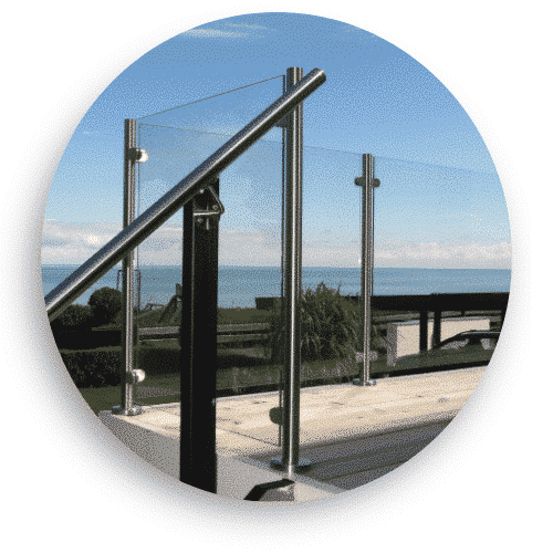 Modernes Glasgeländer mit Edelstahlpfosten und Handlauf auf einer Terrasse mit freiem Blick aufs Meer.