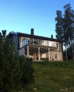 Aluminium-Glasgeländer rund um Balkon eines zweigeschossigen Hauses mit Säulen und Loungebereich unter der Terrasse.